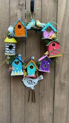 a wreath made out of bird houses hanging on a fence