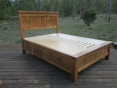 a wooden bed frame sitting on top of a wooden floor next to a forest filled with trees