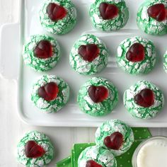 green and white cookies with cherries in the shape of hearts on a platter