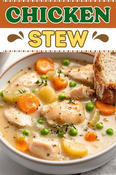 chicken stew in a white bowl with carrots, peas and bread on the side