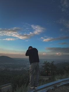 a man standing on top of a hill looking at the sky