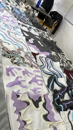 several pieces of cloth are laid out on the floor in rows, all with different patterns and colors