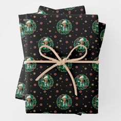 two presents wrapped in black wrapping paper with green and red designs on them, tied together