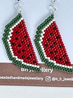 two watermelon slices are hanging from the back of a pair of beaded earrings