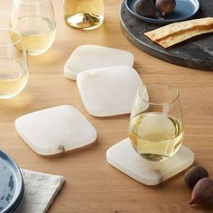 several glasses of wine and some food on a wooden table with plates, bowls and utensils