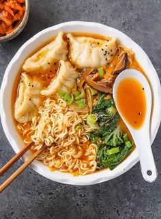 a bowl filled with noodles, meat and veggies next to some chopsticks