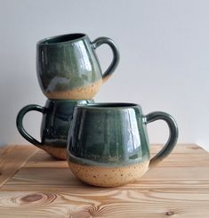 two green mugs sitting on top of a wooden table