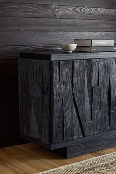 a black wooden cabinet sitting on top of a hard wood floor next to a wall