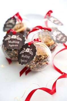 three small glass ornaments with red ribbon on them and tags attached to the top of each ornament