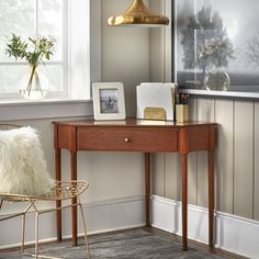 a room with a desk, chair and pictures on the wall next to a window