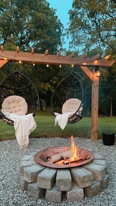 an outdoor fire pit with hanging chairs and lights