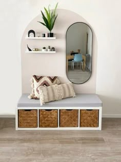 a white bench with baskets under it and a mirror above it on the wall behind it