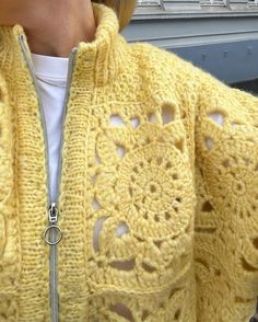 a woman wearing a yellow crocheted jacket with holes in the front and bottom