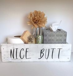 a wooden sign that says nice but with toilet paper and tissue dispenser