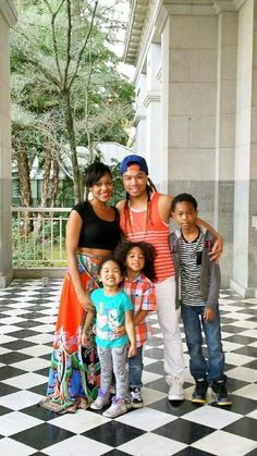 the family is posing for a photo on the checkered floor in front of an old building