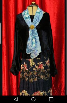 a woman's black dress with floral print on it and blue scarf around the neck