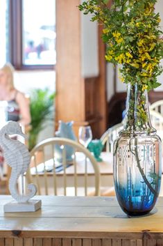 there is a vase with yellow flowers in it on the table next to a seahorse figurine