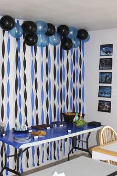 a party room with balloons and black and white wallpaper on the walls, blue table