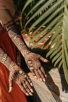 a woman's hands with hennap on her hand and palm tree in the background