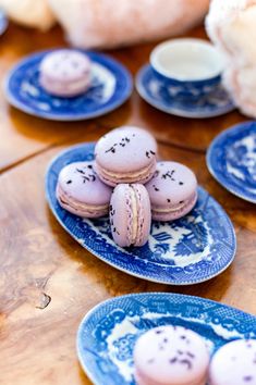 blue and white plates filled with macaroons on top of a wooden table next to bread