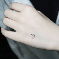 a woman's hand with a small crescent tattoo on the left side of her wrist