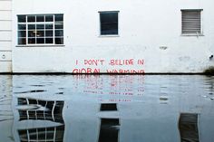 the reflection of a building in water with graffiti on it's wall and windows