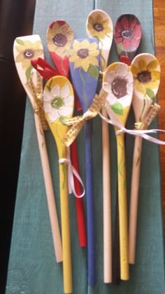 five wooden spoons with flowers painted on them are lined up against a green cloth