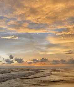 the sun is setting over the ocean with clouds in the sky and waves crashing on the beach