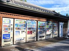 a row of vending machines sitting next to each other on a side walk in front of a building