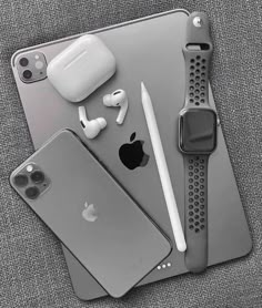 an iphone, headphones, and other electronics are arranged on top of a gray surface