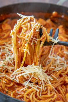 a spoon full of spaghetti being lifted from a skillet