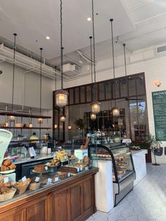 the inside of a restaurant with lots of food on display and hanging lights above it