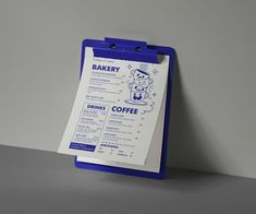 a blue and white clipboard with a menu attached to it on a gray surface