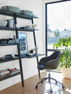 a room with a chair, bookshelf and potted plant