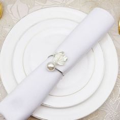 a white plate topped with a napkin and a flower ring on it's end