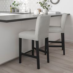 two stools in front of a kitchen counter with a clock on the wall behind them