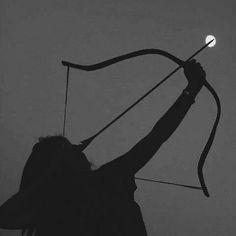 the silhouette of a person holding a bow and an arrow in their right hand, against a foggy sky