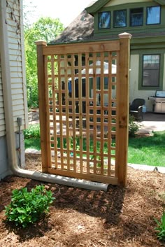 a wooden gate sitting in the middle of a yard next to a house on a sunny day