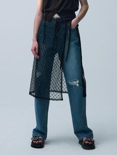 This product is an innovative lace wrap skirt that overlays a pair of classic jeans, offering a unique blend of textures and styles. The skirt features a delicate lace pattern with a translucent appearance, adding a layer of sophistication and visual interest. It ties at the waist with a sleek, adjustable ribbon, allowing for a customized fit while highlighting the contrast between the rugged denim and the refined lace. - This skirt features a distinctive lace design that wraps around and ties at the waist, providing a versatile and adjustable fit.- The lace is designed with an intricate pattern that adds a touch of elegance and complexity to the overall appearance.- Paired with rugged denim jeans, the lace offers a striking contrast that blends casual and upscale fashion elements.- T Sheer Wrap Skirt, Chic Relaxed Lace Skirt, Flowy Asymmetrical Lace Skirt, Lace Asymmetrical Skirt With Lace Trim, Rugged Denim Jeans, Denim Skirt Lace, Denim Wrap Skirt, Upscale Fashion, Fashion Elements