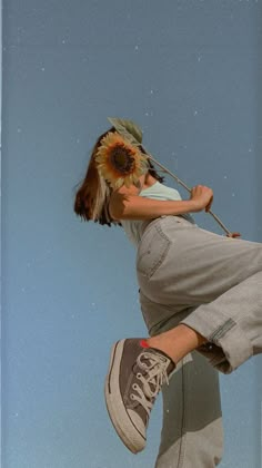 a person jumping in the air on a skateboard with a sunflower attached to their head