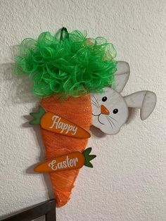 an orange carrot with green hair on it's head is hanging from the wall