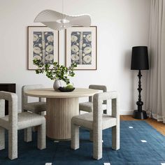 a dining room table with four chairs and a vase on the centerpiece in front of it