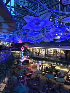 the interior of a shopping mall with blue lights and umbrellas hanging from the ceiling