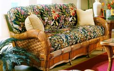 a living room with wicker furniture and flowers on the couch, coffee table and rug