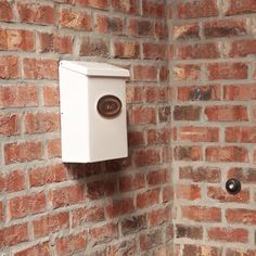 a brick wall with a white box mounted to it's side next to a toilet paper dispenser