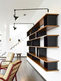 a room that has some shelves on the wall and chairs in front of it,