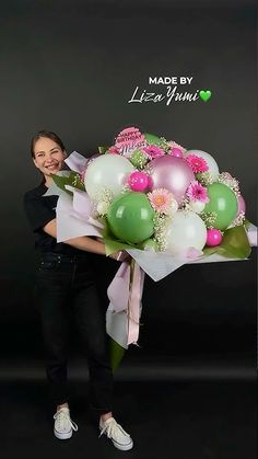 a woman holding a bouquet of flowers and balloons in front of a black background with the words made by life's primes written on it