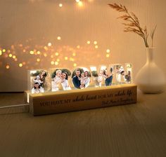 a book with four photos on it sitting next to a vase and string lights in the background