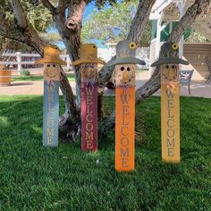 three wooden scarecrows with hats on their heads are standing in front of a tree