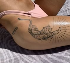 a woman laying on top of a bed with a tiger tattoo on her arm and leg